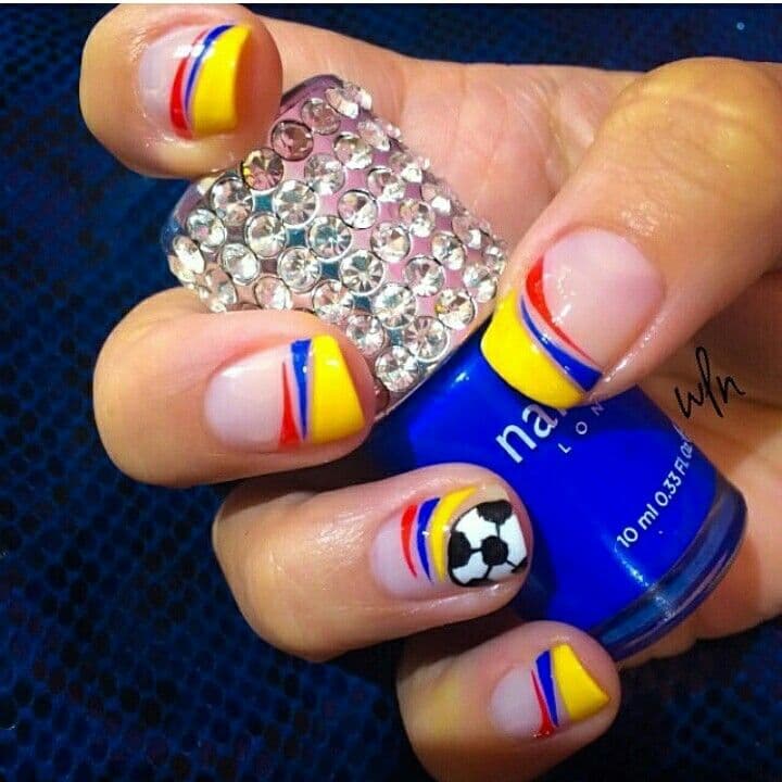 Uñas con francesas en los colores de la bandera de Colombia —amarillo, azul y rojo— con detalles en cristales y un balón de fútbol