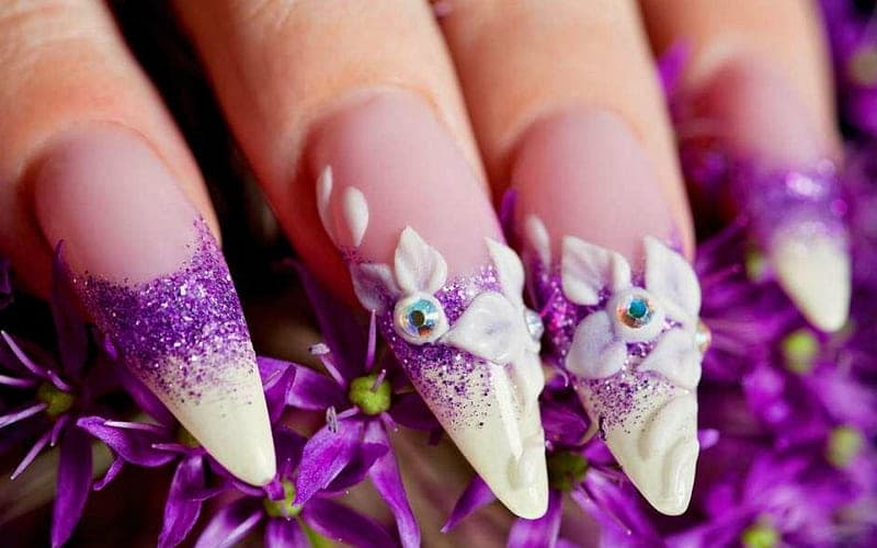 Uñas stiletto con degradado de escarcha violeta, flores blancas en 3D y cristales